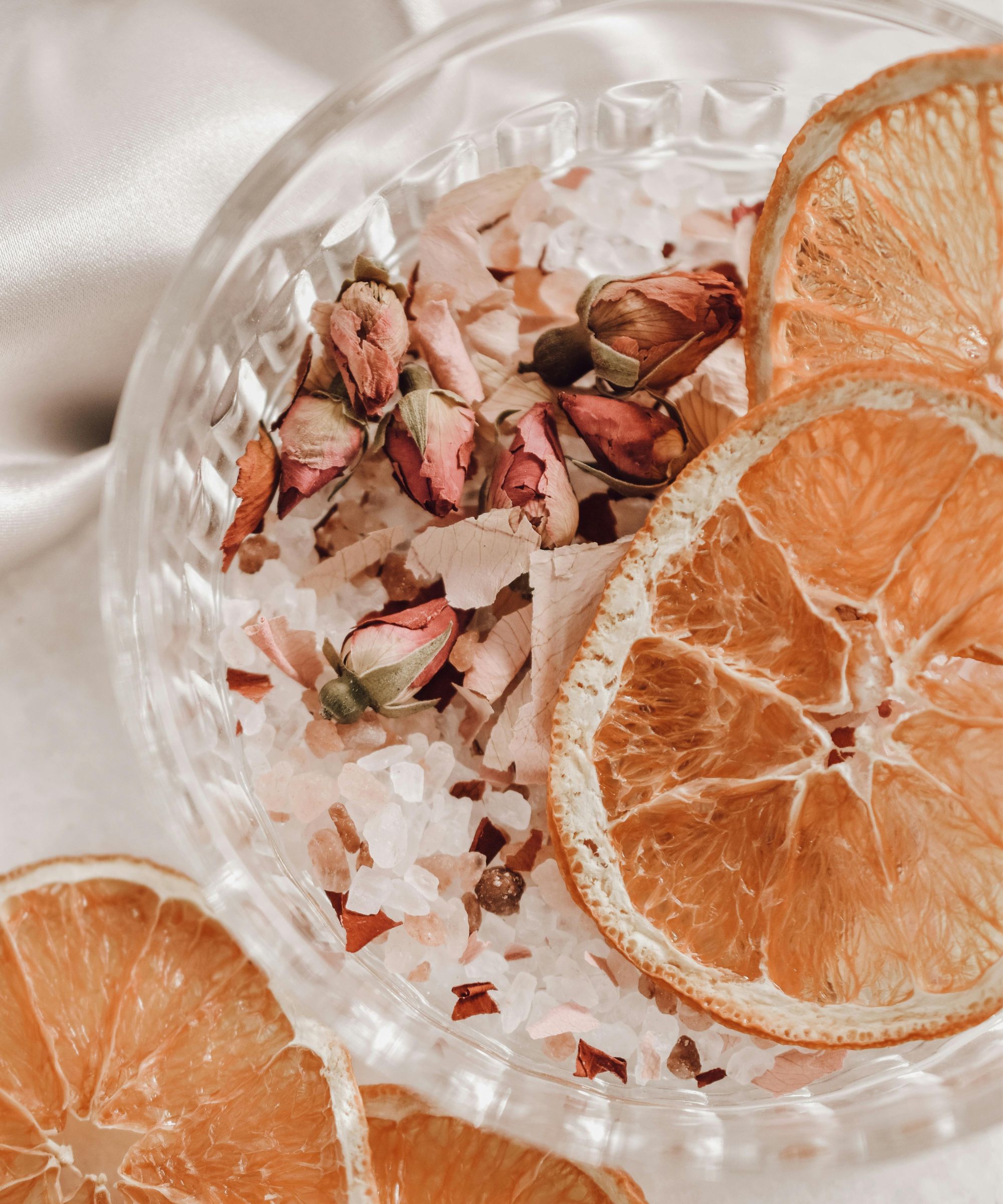 Aerial view of ribbed glass bowl with dried rose petals and orange slices