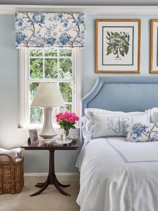 A bedroom with blue headboard and white patterned linen