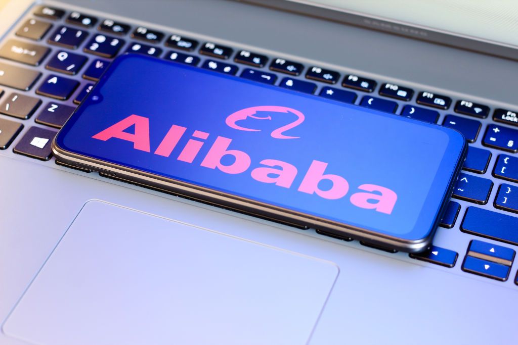 Alibaba logo on a smartphone that&#039;s placed on top of a laptop keyboard