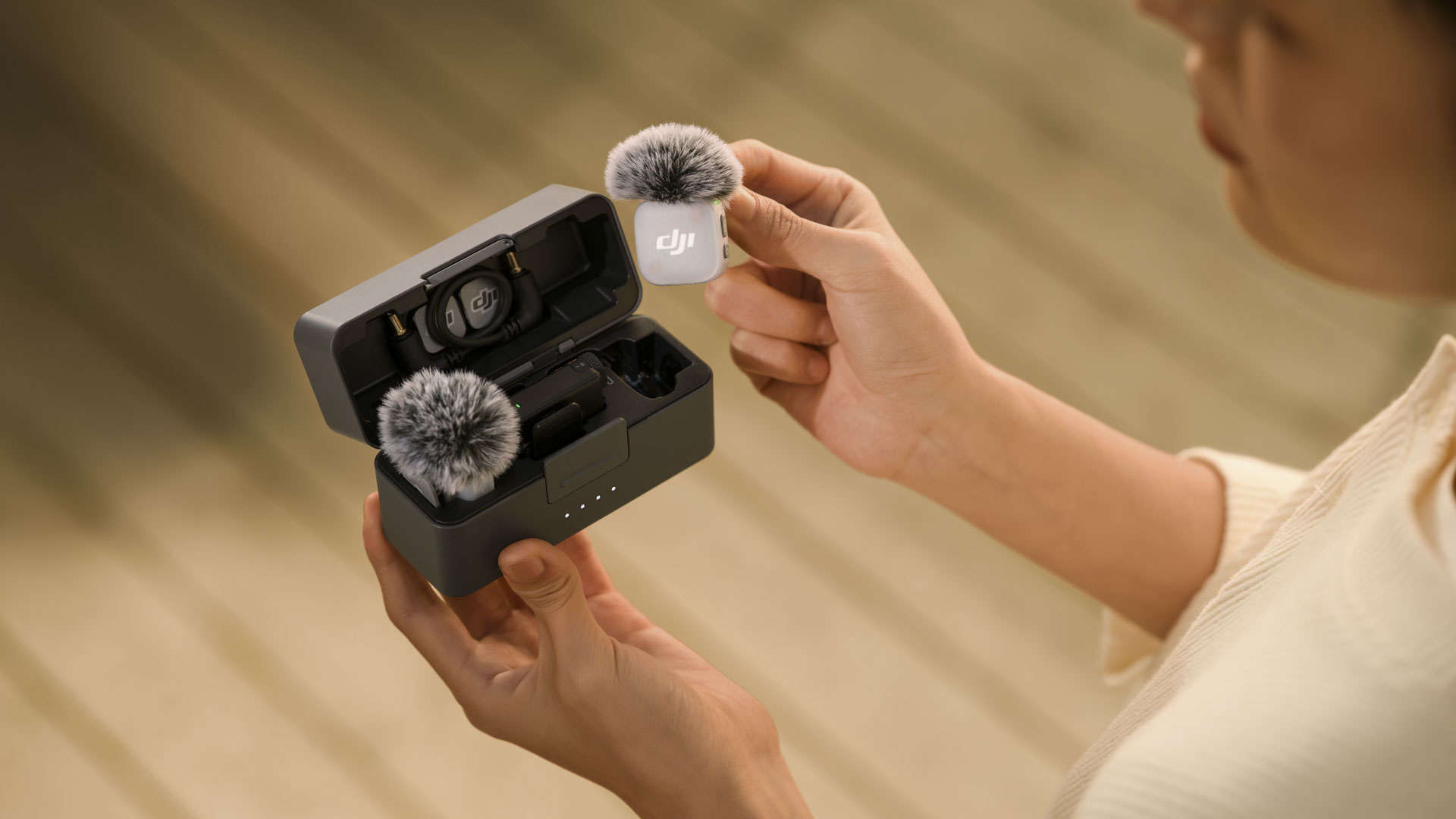 DJI Mic Mini 2 charging case in person's hands and they are taking out one of the mics