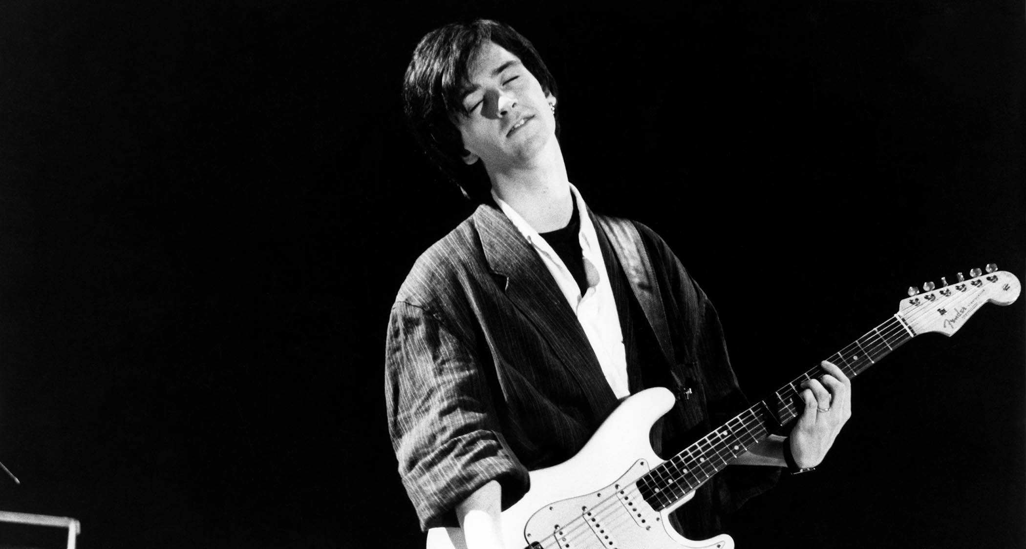 Johnny Marr plays a chord on his white Stratocaster as he performs live with the Smiths in 1987