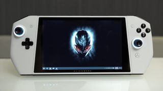 Alienware UFO concept handheld on white surface with themed desktop on screen