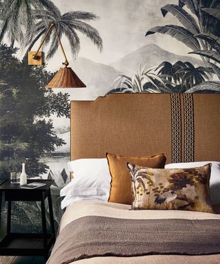 Wall decor for bedrooms featuring gray tropical print wallpaper and an ochre linen headboard and pillows.