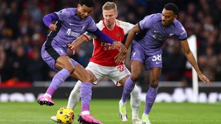 Oleksandr Zinchenko of Arsenal, in white and red, tangles with Cody Gakpo and Ryan Gravenberch of Liverpool in all purple strip.