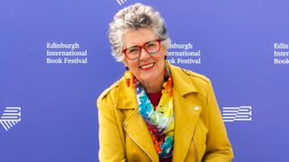 Dame Prue Leith wearing a yellow coat and smiling 