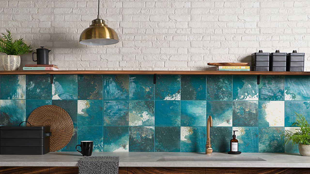 Painterly teal backsplash tiles with brass pendant light and white brickwork.