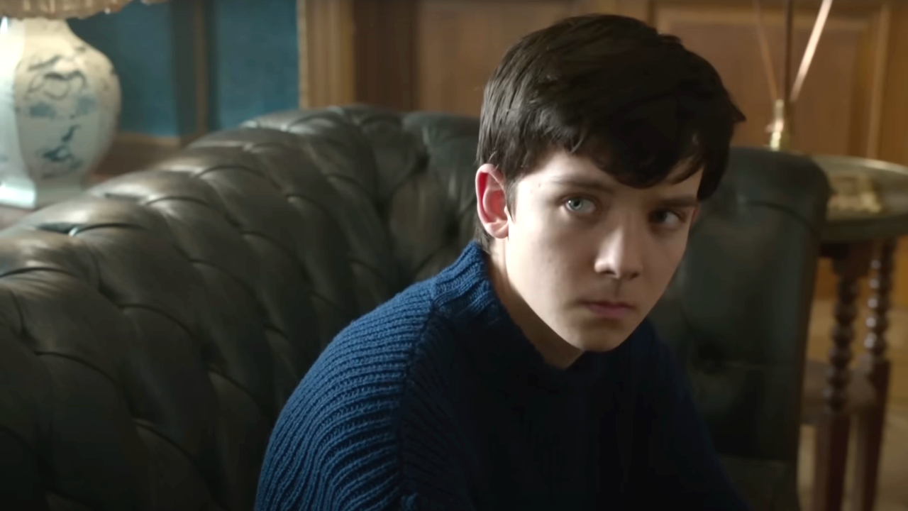 Asa Butterfield sits on a fancy couch looking confused in Miss Peregrine's Home for Peculiar Children.