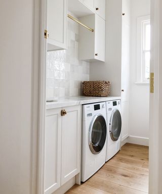 Utility room with laundry machines and white cabinets