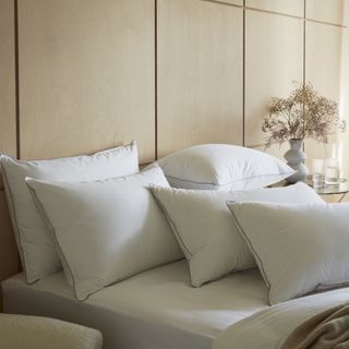 White pillows layered on bed in neutral bedroom