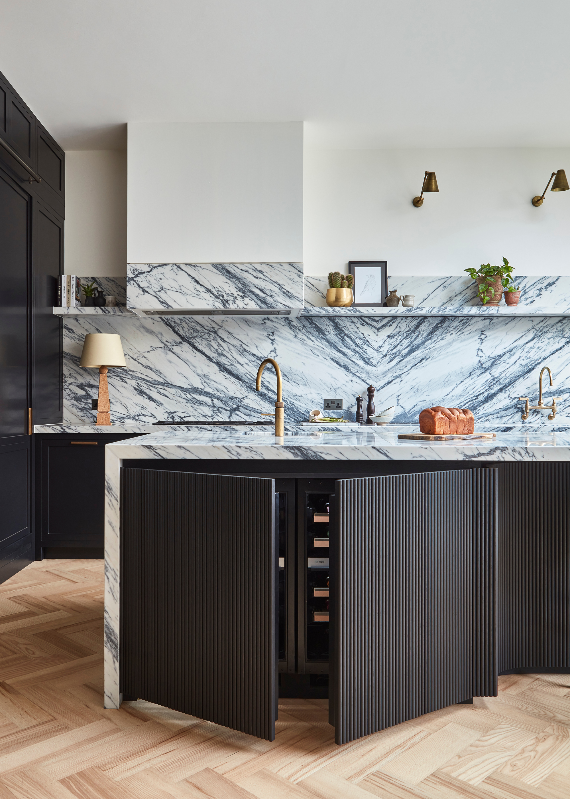 A striking book matching marble worktop and backsplash with a hidden wine fridge in the island