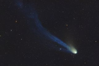 El cometa del diablo aparece como un núcleo verde y una larga cola azul con una curvatura.