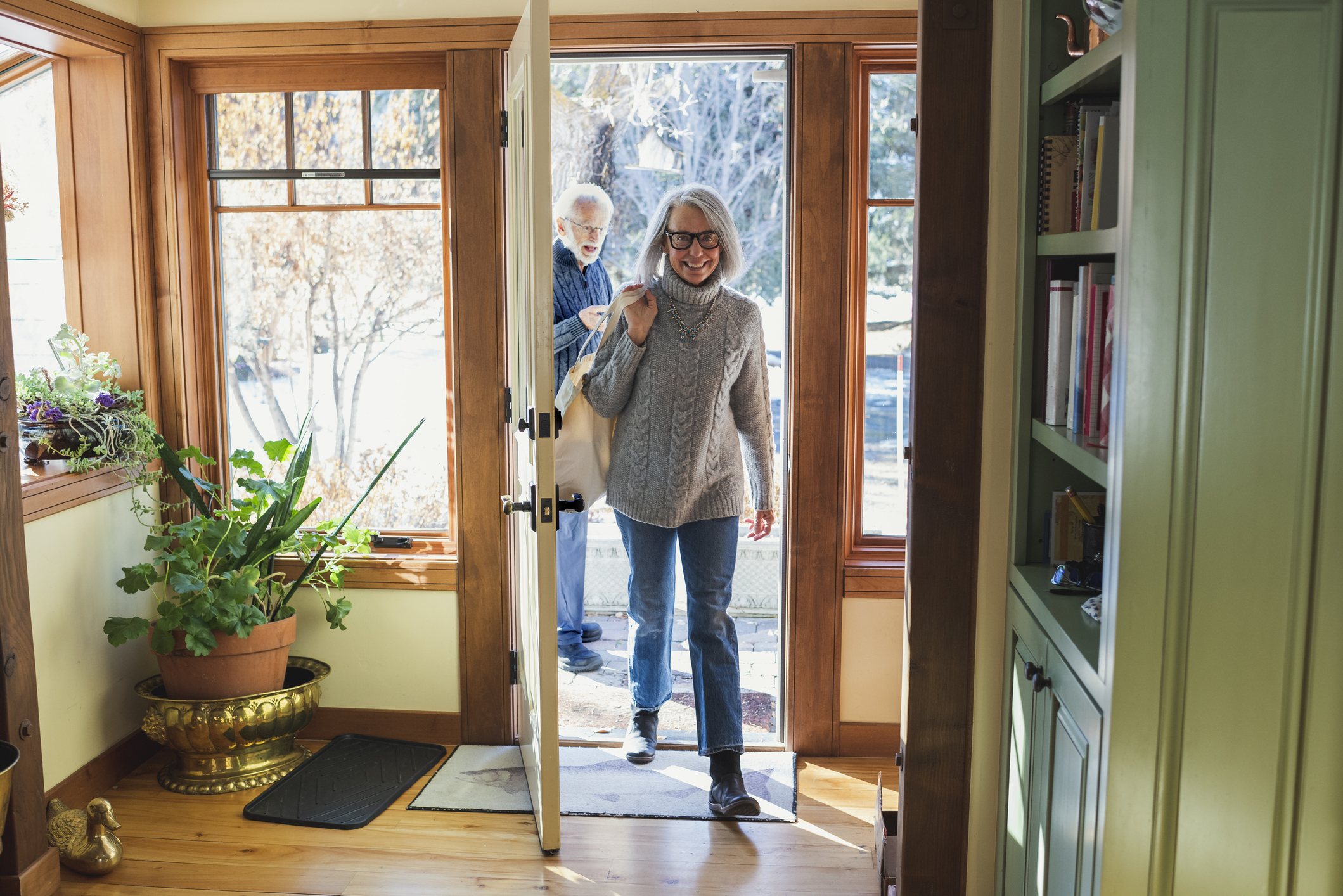 A man and woman in their 70s arrive home after shopping.