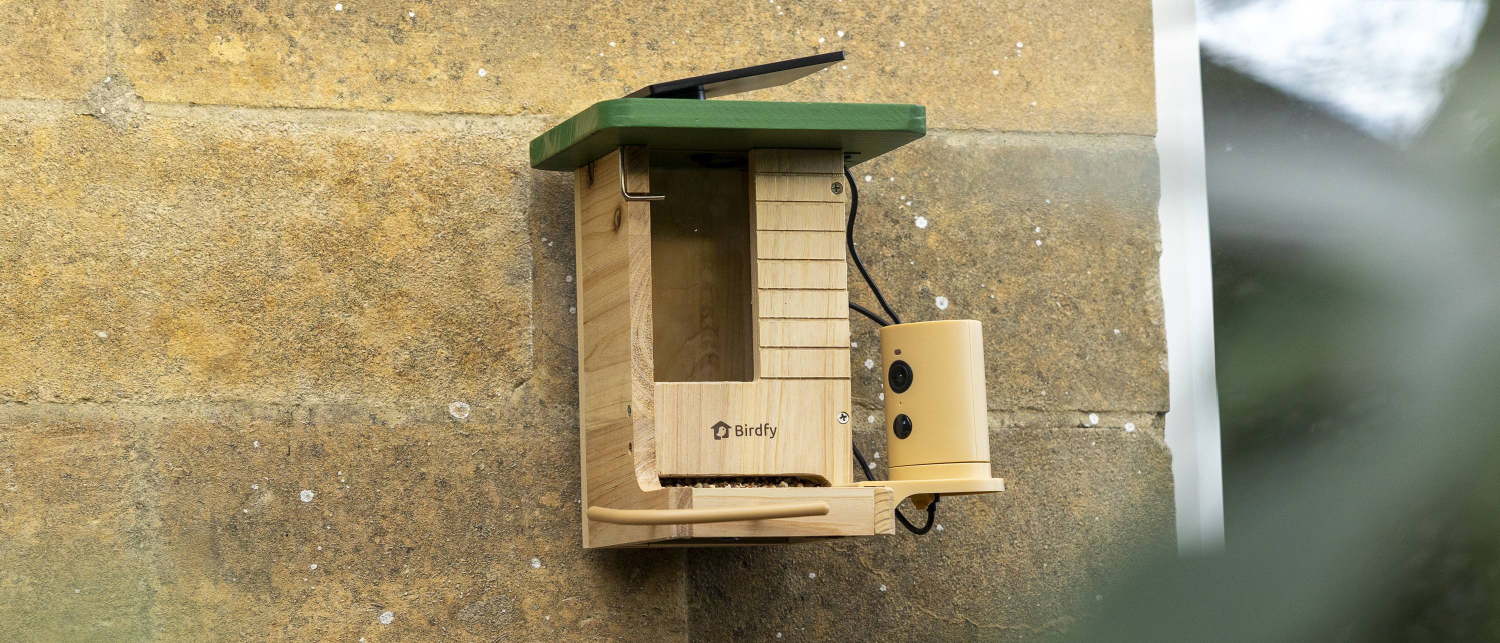 The Birdfy Wood feeder attached to a sandstone wall