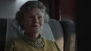 Queen Elizabeth II smiles as she sits on a chair in The Crown season 5