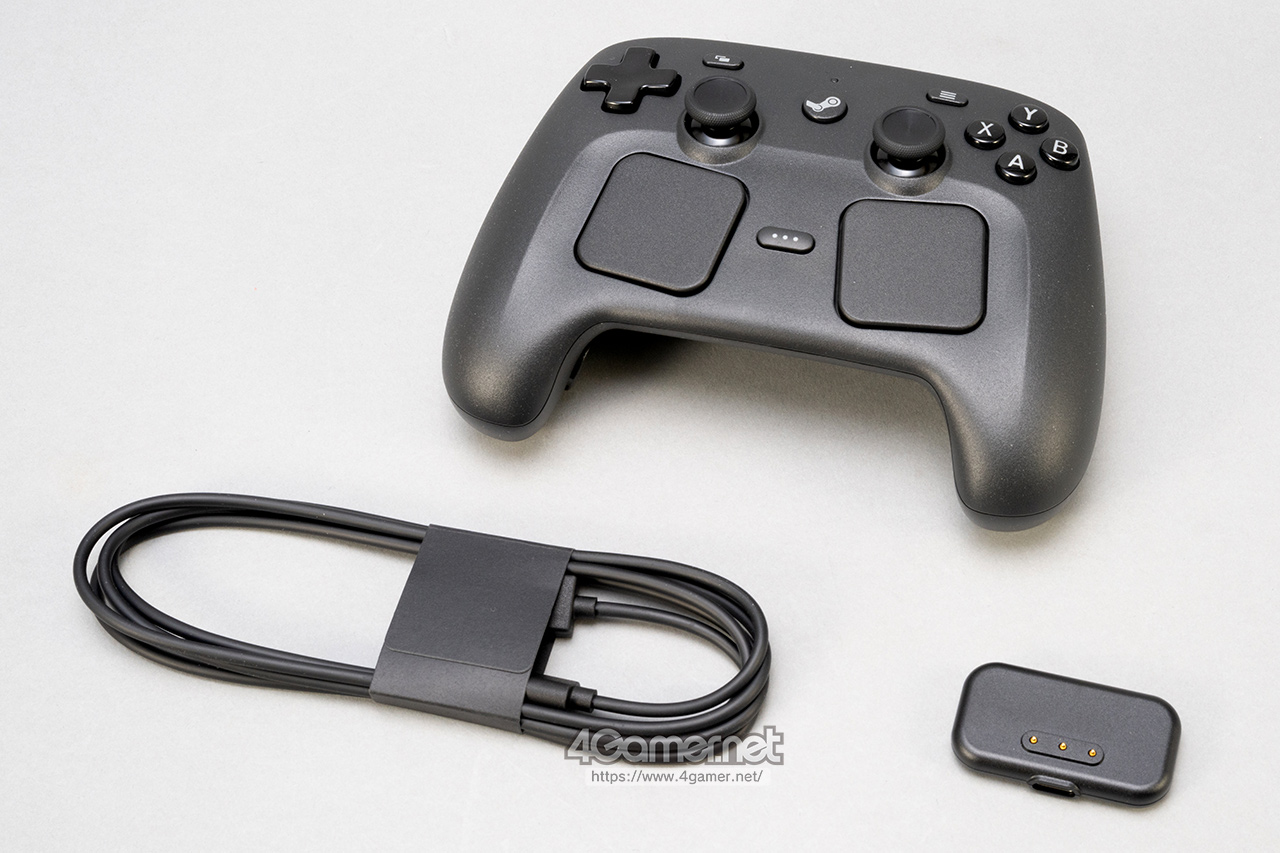 A black gaming controller with dual joysticks and a button layout, accompanied by a USB cable and a charging dock, set on a light gray background.