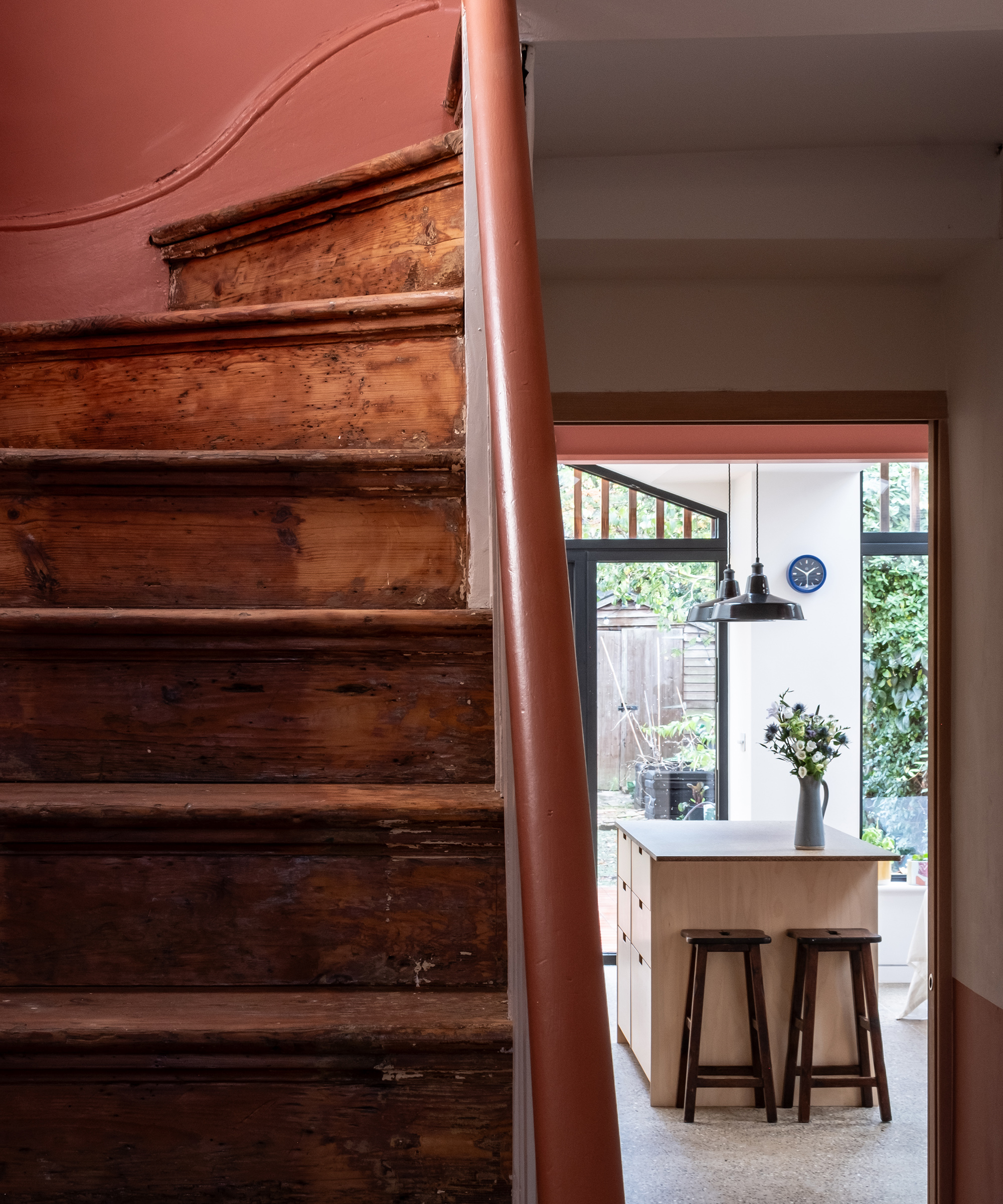 An original wood staircase and pale terracotta coloured rail. There is a kitchen extension down the hallway with lots of natural light