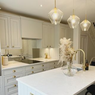 neutral kitchen with island unit and gold tap, plus mirrored splashback