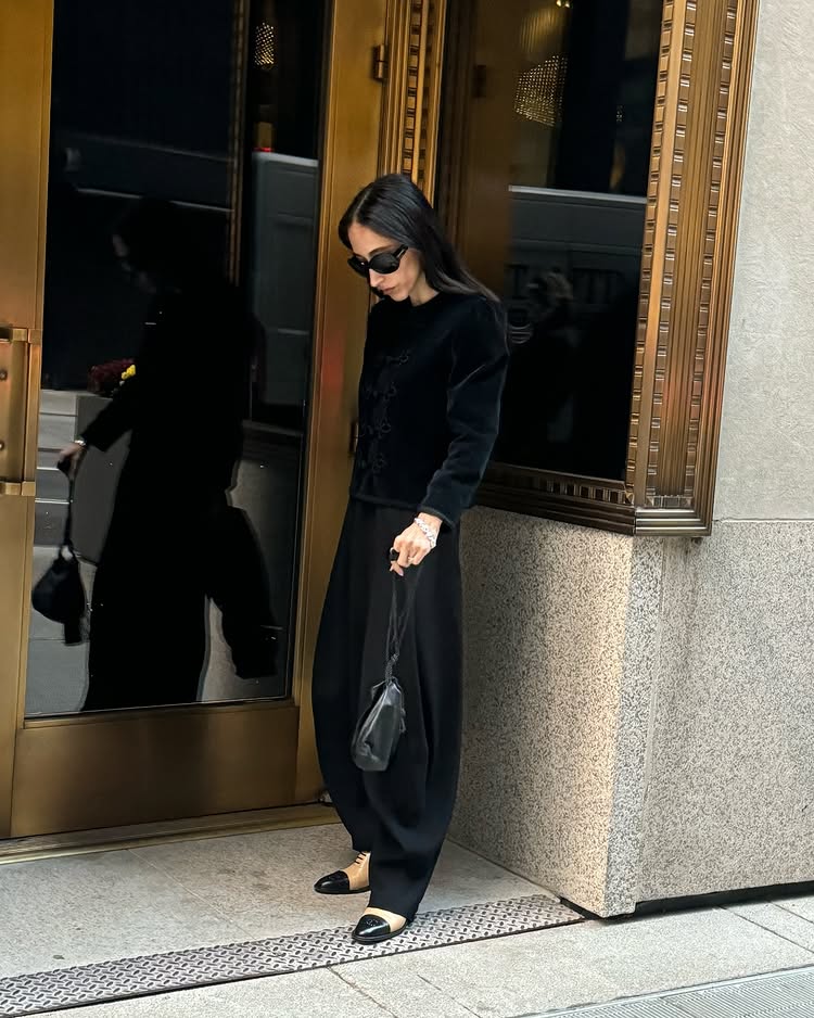 An image of @alexisbadiy wearing a black collarless jacket, black barrel leg trousers and two-toned derbies from Chanel.