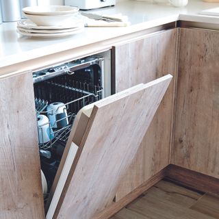 Kitchen with faux-oak cupboards and slimline dishwasher half open.