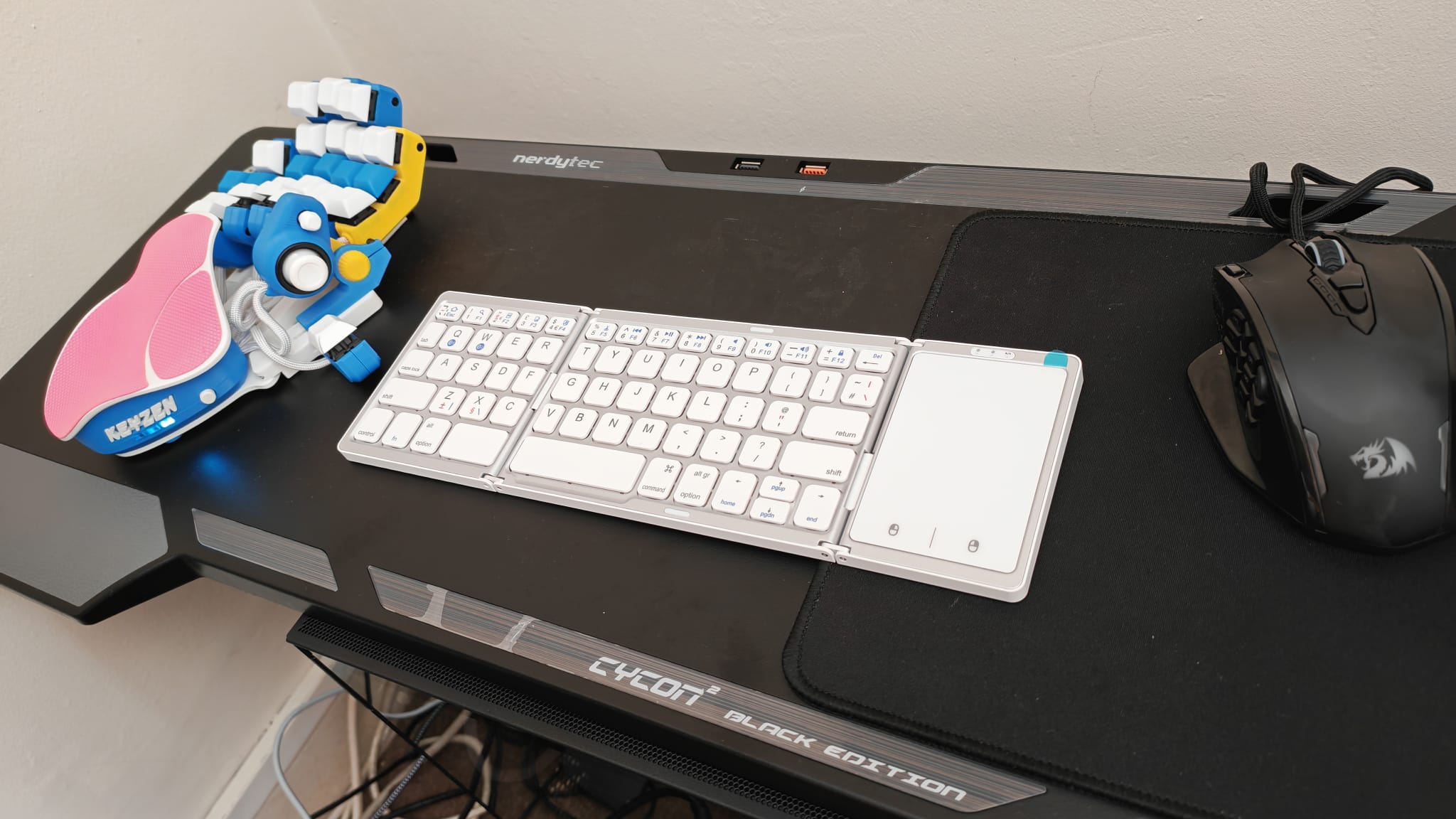 The SEENDA Foldable Bluetooth Keyboard unfolded next to an Azeron Keyzen