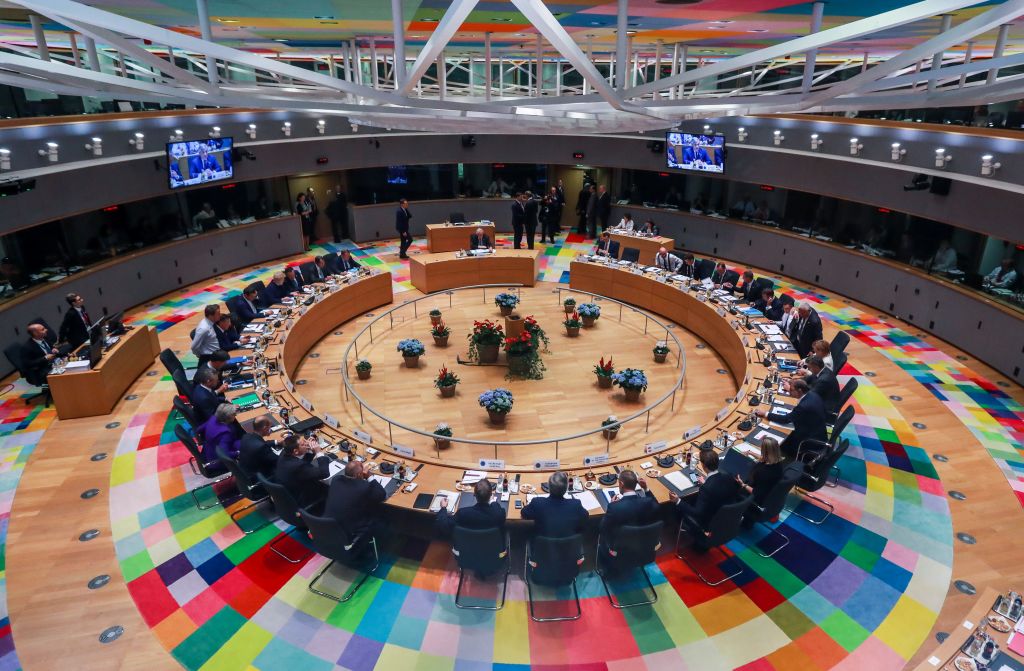 An top down view of the circular meeting table at the European Commission, with various European leaders sat in attendance