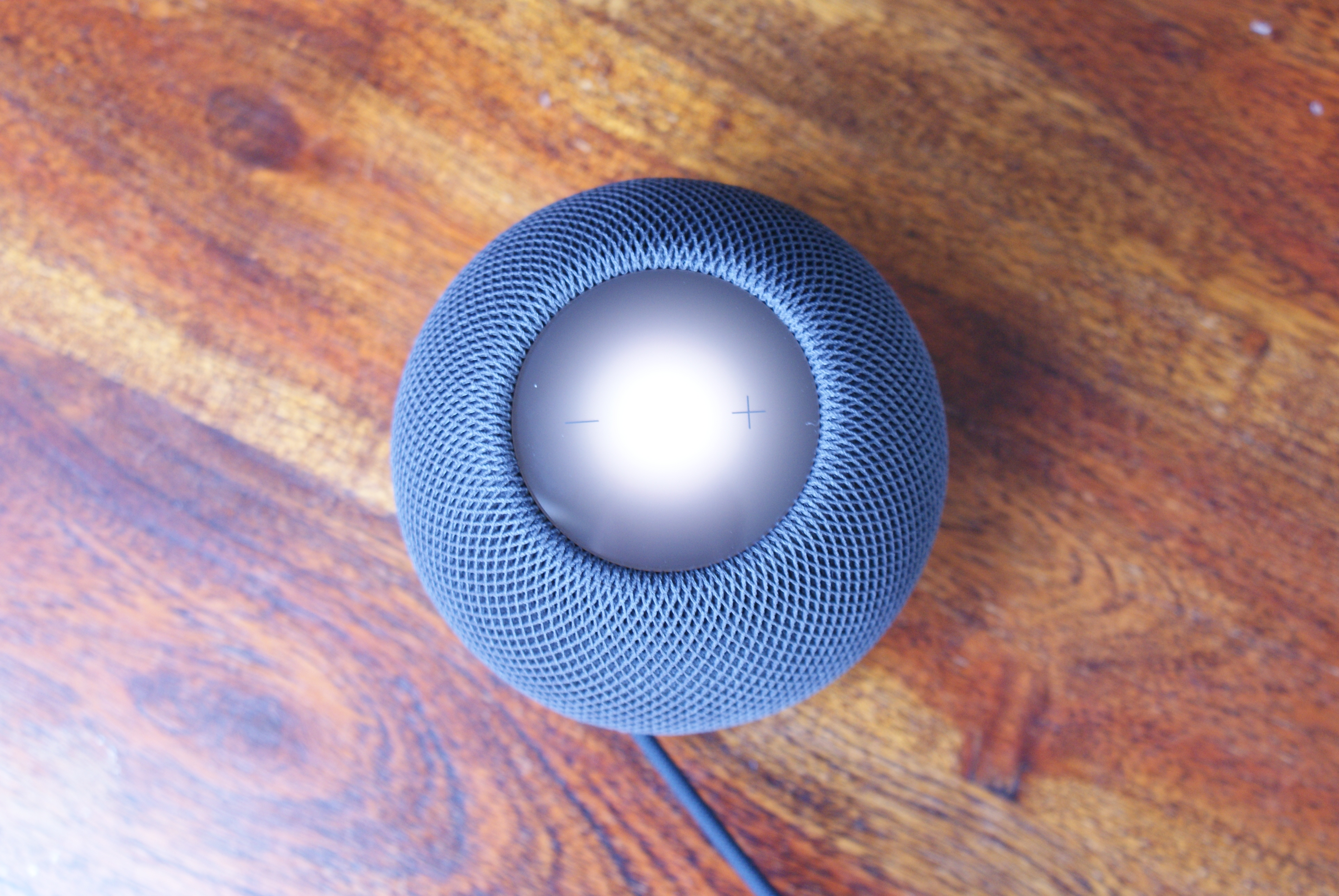 En smart-høyttaler av typen HomePod mini på en bordplate.