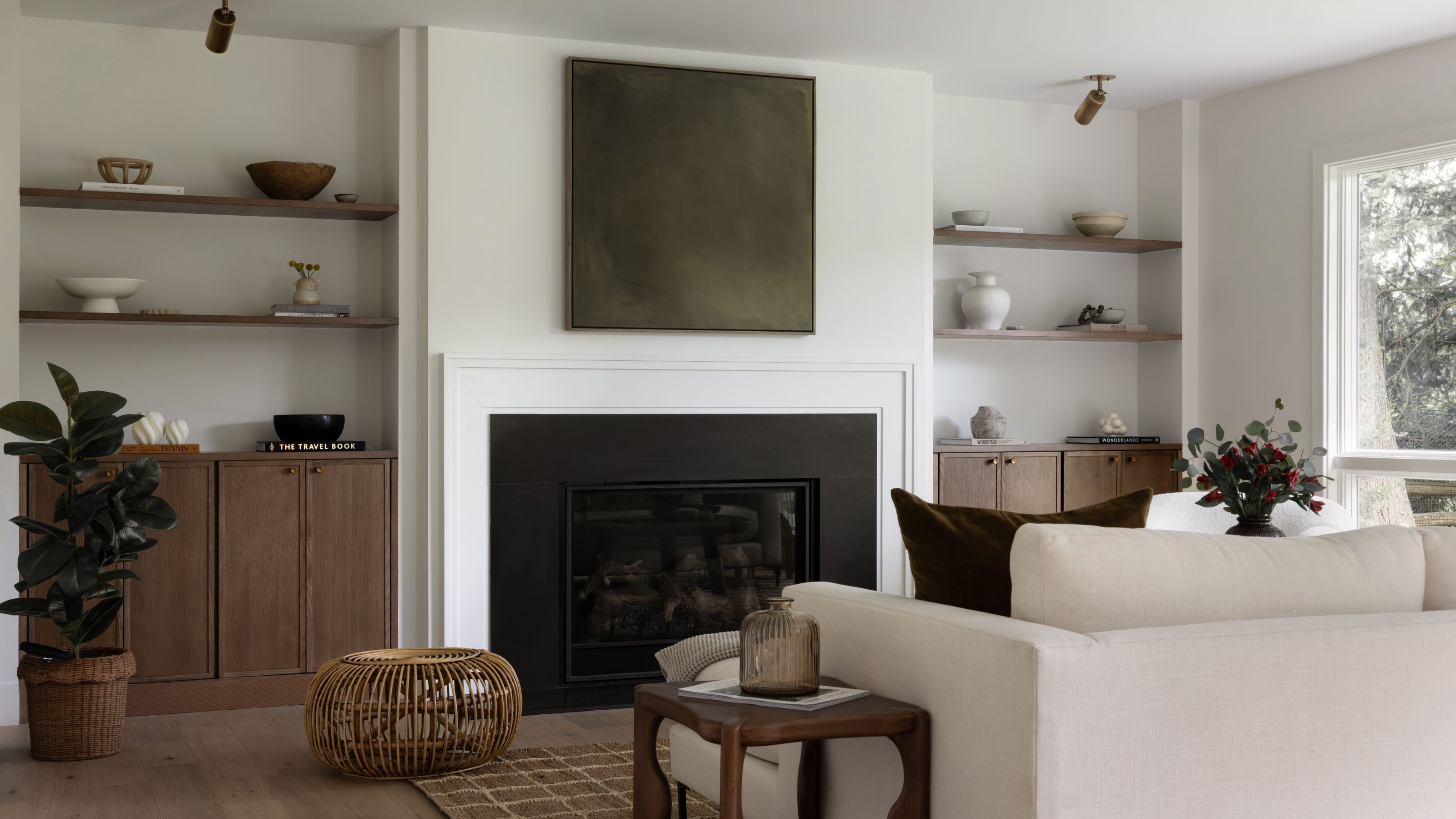 neutral living room with alcove shelving and large fireplace and artwork