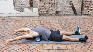 Man stretching with foam roller underneath him