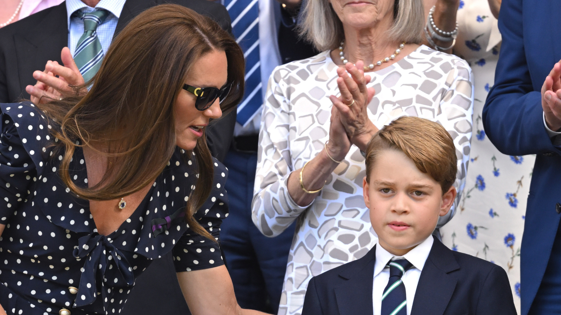 Kate Middleton wears a polka dot dress and sunglasses and talks to son Prince George who wears a navy suit with a striped tie