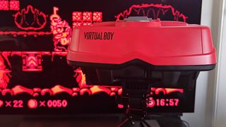 Close up of Virtual Boy headset with Wario Land gameplay in backdrop.