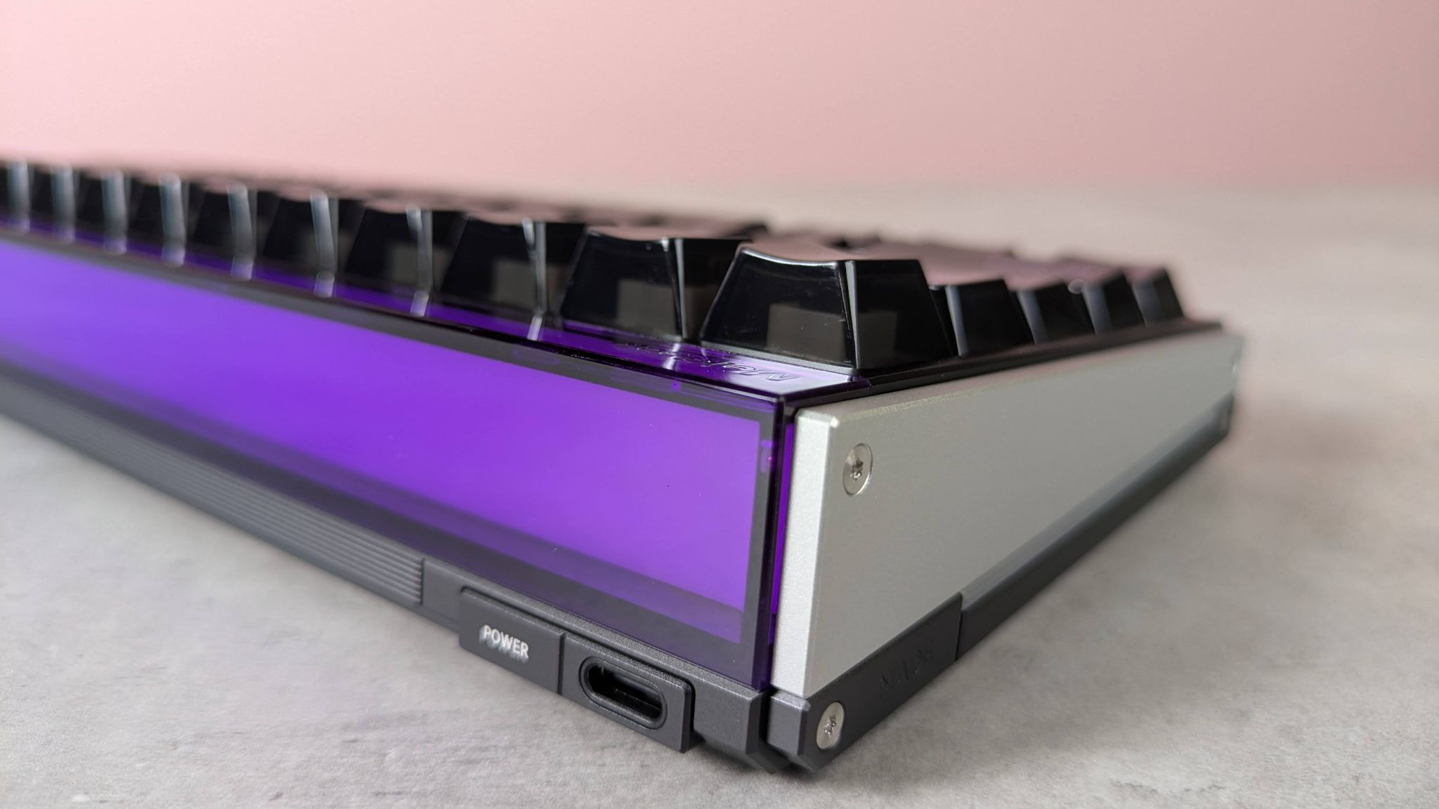 Close-up of rear corner of MelGeek Made68 Ultra V2, on desk with pink wall in background
