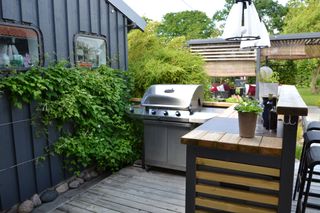 An outdoor kitchen with a gas grill on decking
