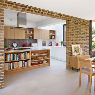 wooden kitchen island and cabinets with exposed brick wall