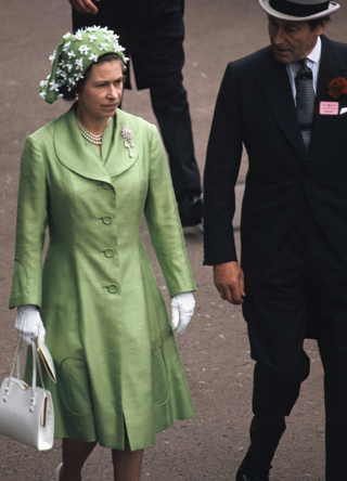 Queen Elizabeth II (1926 - 2022), accompanied by an unidentified man, arrives at the Royal Ascot at Ascot Racecourse, Ascot, England, 1973