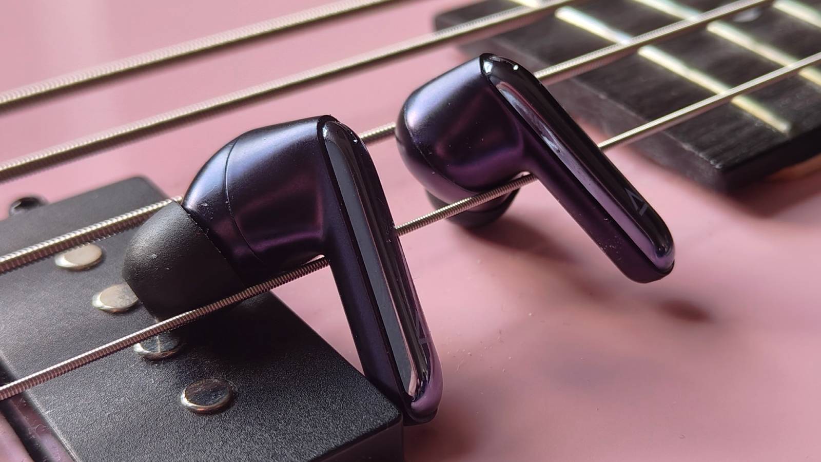 The Creative Aurvana Ace 3 buds and case on a pink bass guitar.