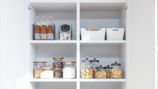 A view inside and organised kitchen cabinet with ingredients stored in glass jars