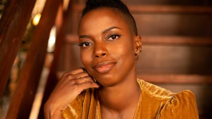 A portrait of Sasheer Zamata, sitting on a staircase.