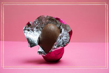A half unwrapped Easter-egg in pink foil on a pink background