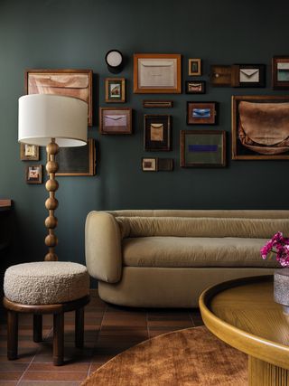 A living room painted dark teal with a gallery wall