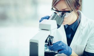 A female scientist looking through a microscope in a laboratory