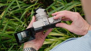 Lumix L10 camera held above plants with its screen flipped out.