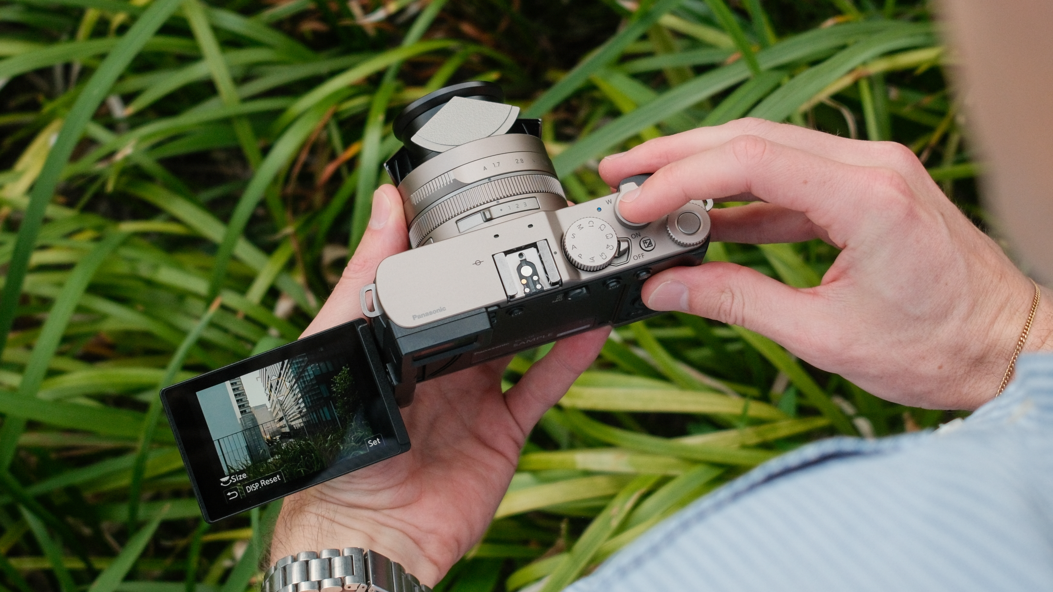 Lumix L10 camera held above plants with its screen flipped out.