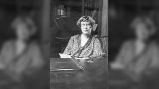 Black and white photo of Matilda Moldenhauer Brooks sitting at a desk with a book in front of her. She is an American cellular biologist.