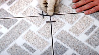 Person placing tile spacers in floor tiles