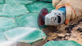 Angle grinder cutting green hexagonal paving slabs