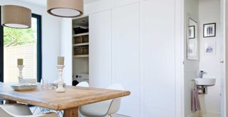 bright white dining room with wall of cupboards with a small cloakroom adjacent to the room