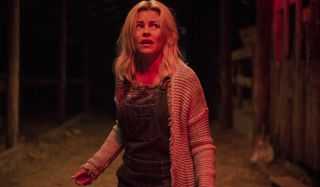 Brightburn Tori looking frightened in the barn, bathed in red light