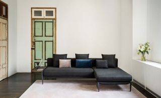 The sofa designed by Michele De Lucchi for Stellar Work is shown here with charcoal upholstery. The sofa is photographed on a cream coloured rug and with a green door in the background
