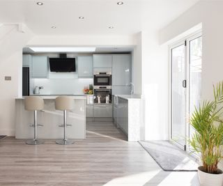 light blue kitchen in large open-plan kitchen dining space with modern patio doors, a breakfast island and vinyl flooring