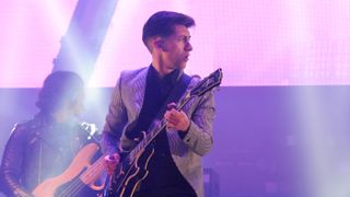 Alex Turner of The Arctic Monkeys plays the guitar on a purple-lit stage at the Glastonbury Festival at Worthy Farm, England.